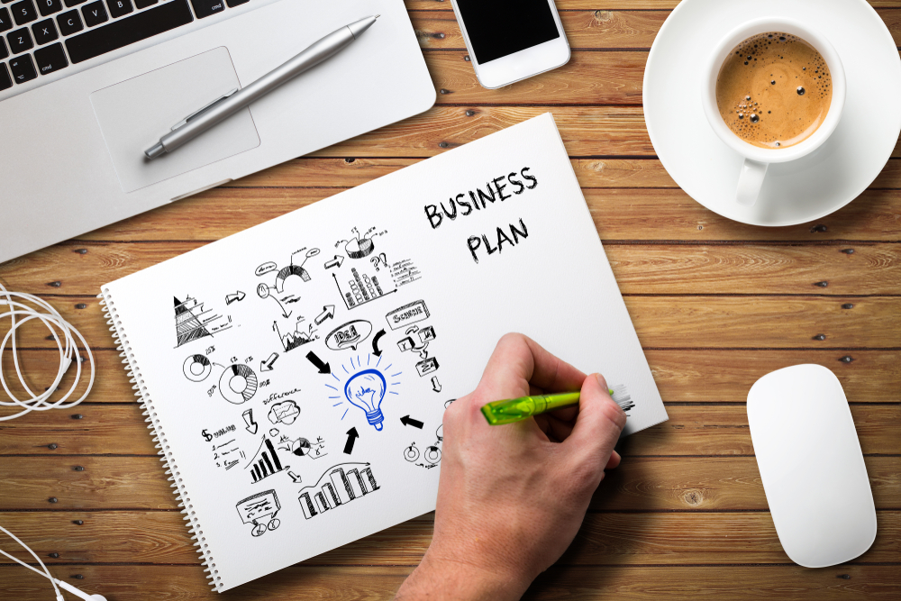 man's hand holding a pen working on a business plan